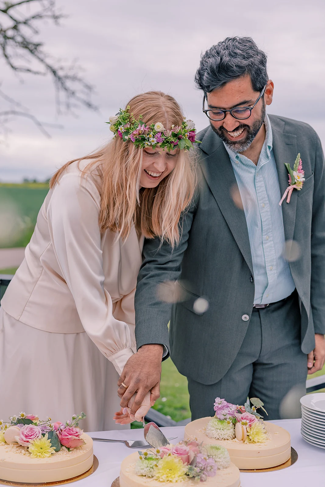 A couple laughing as they cut their wedding cake