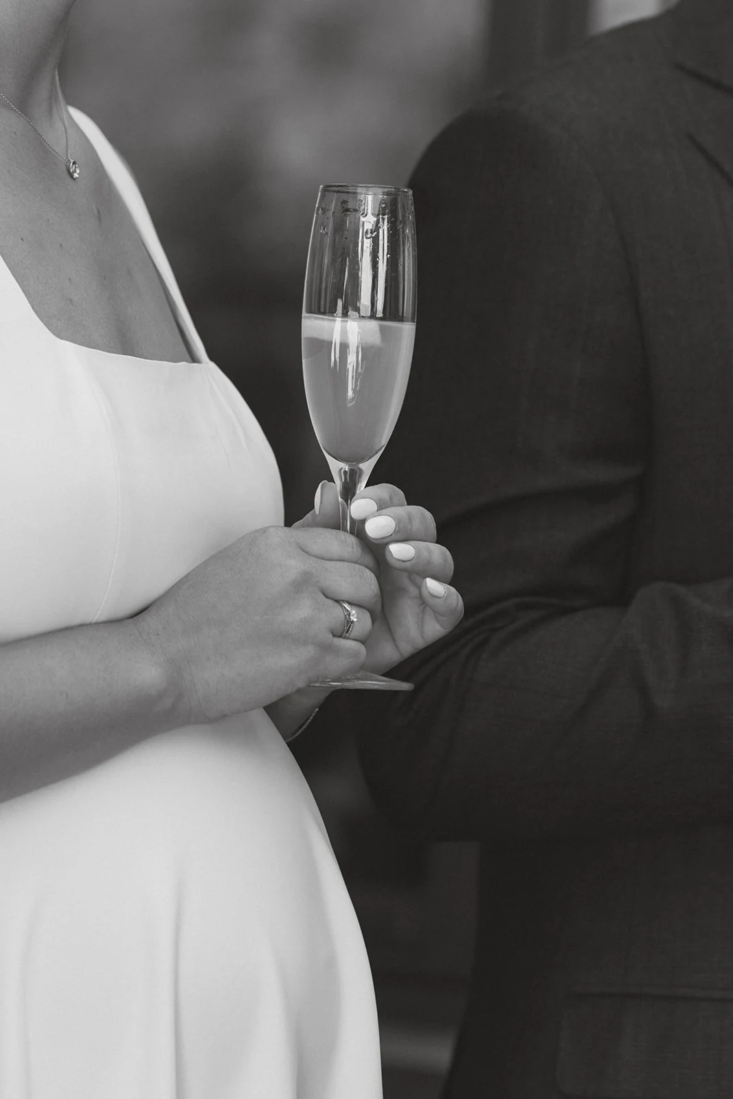 A bride holding a glass of champagne, in black and white