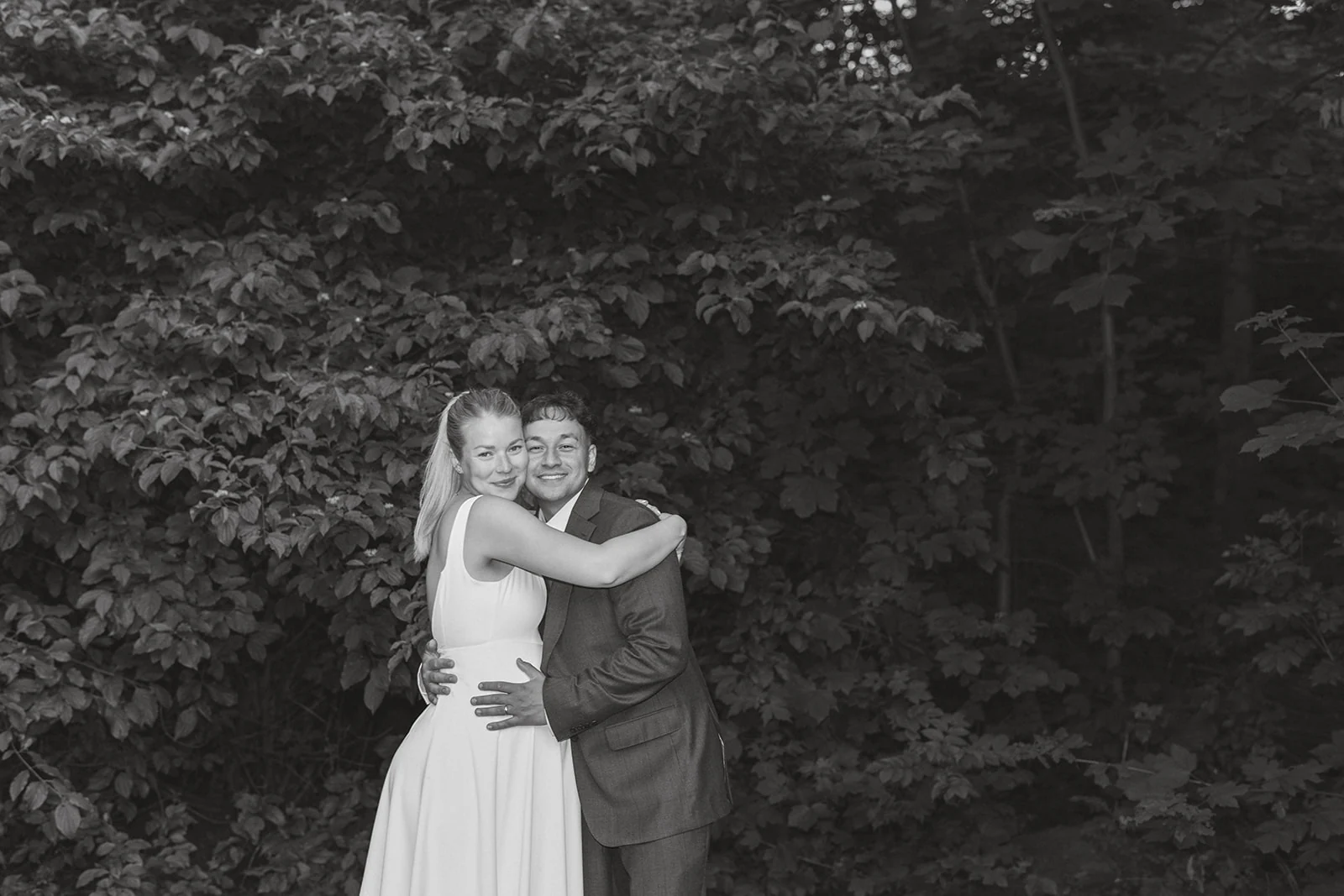 A couple dancing beneath trees, in black and white