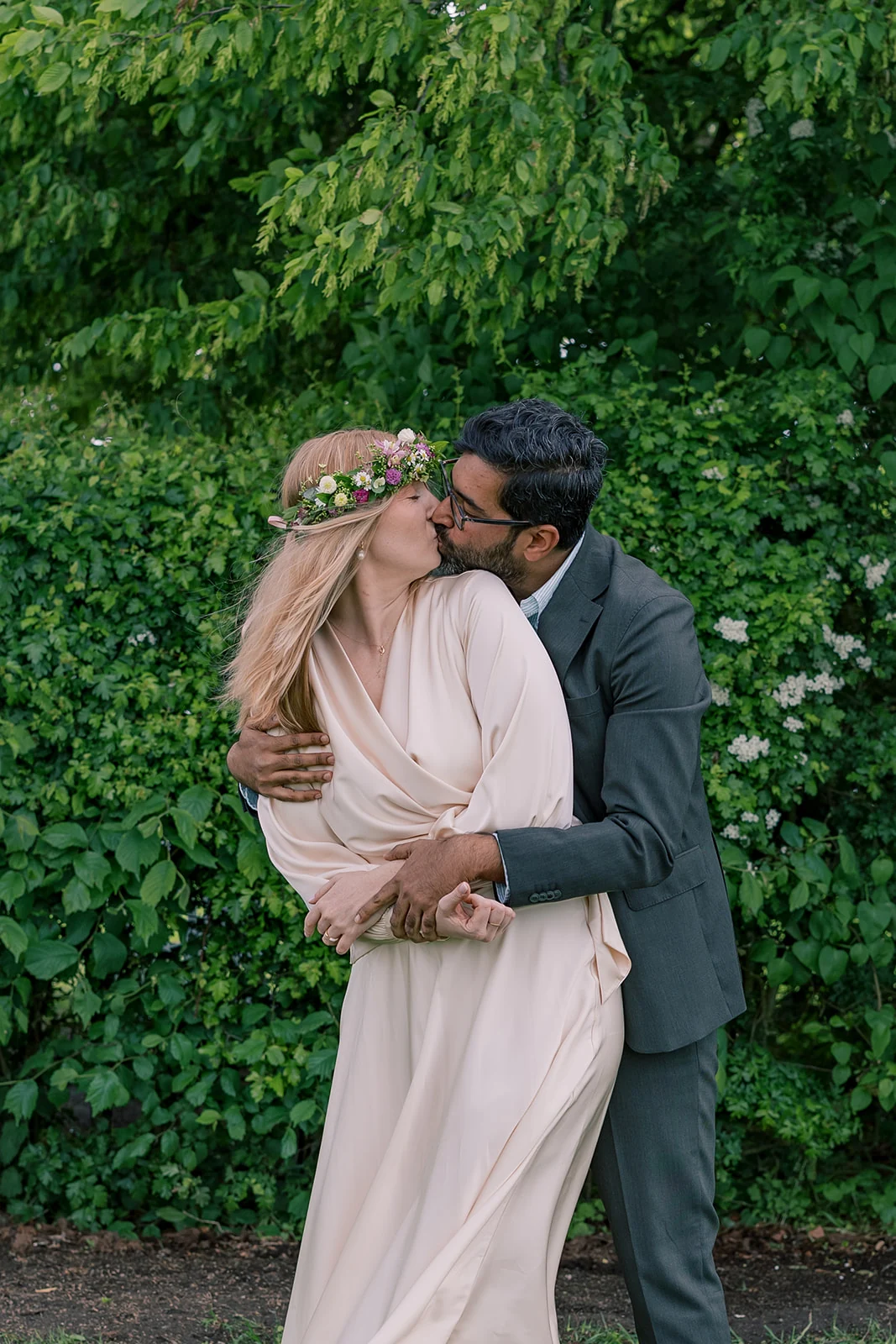 A couple embracing beneath green trees after their wedding