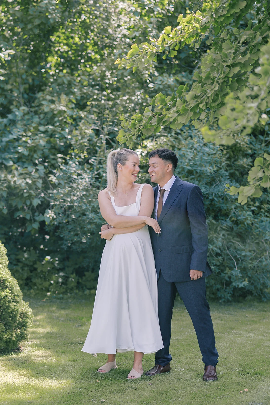 A newly married couple laughing together in a sunlit garden