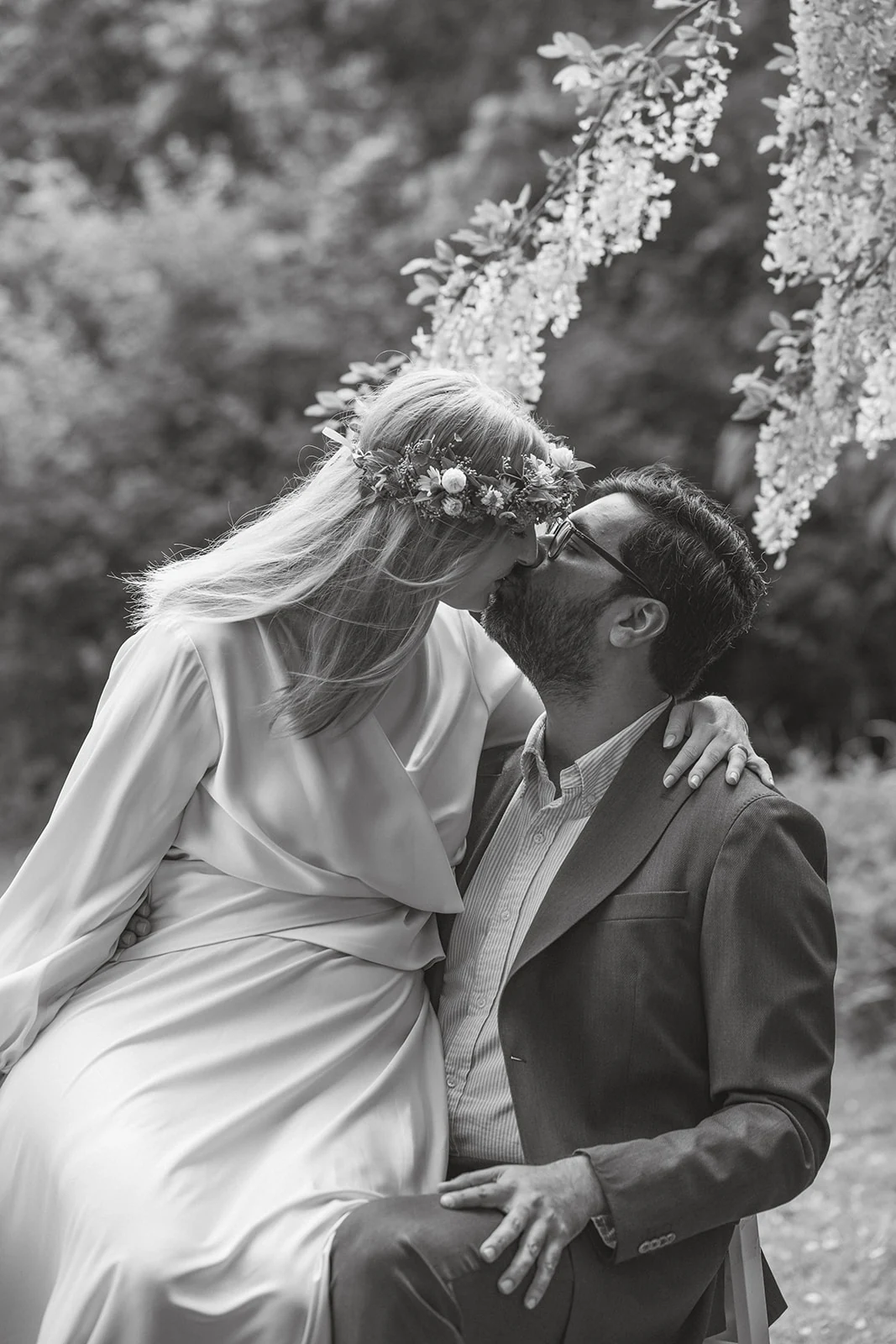 A bride and groom moving together in a garden, in black and white